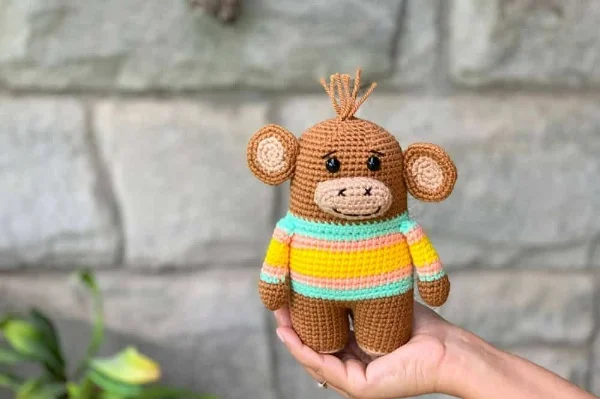 Amigurumi monkey wearing a striped sweater.