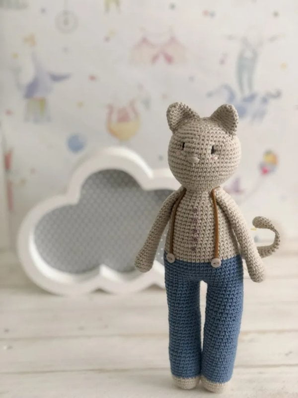 Standing amigurumi cat wearing pants and braces.