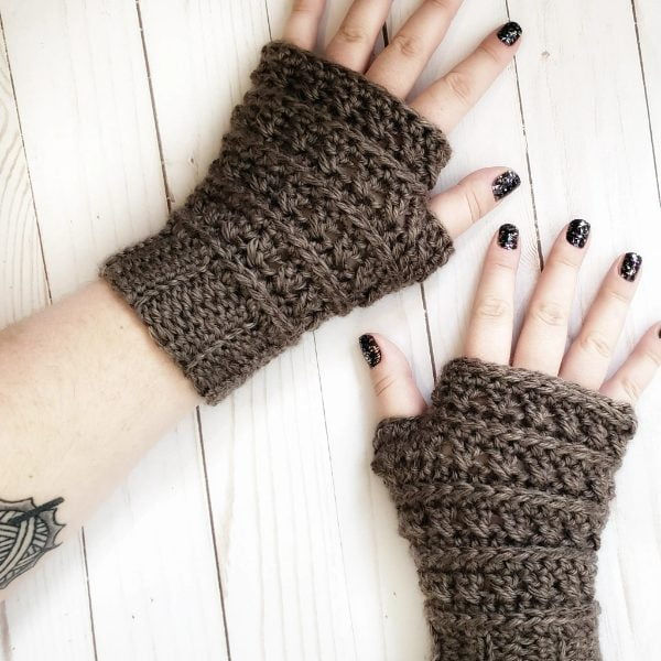 Person wearing brown crochet fingerless mittens.