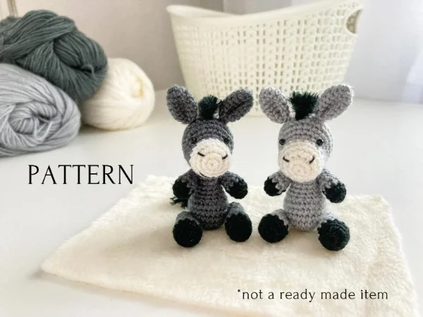 Two little crochet donkey amigurumi sitting together.