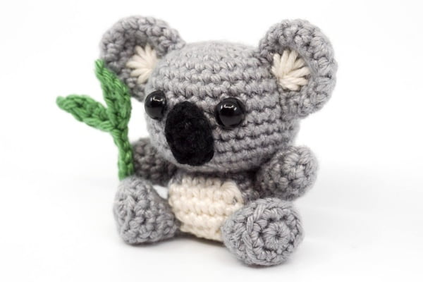 Tiny amigurumi Koala holding a gum leaf.