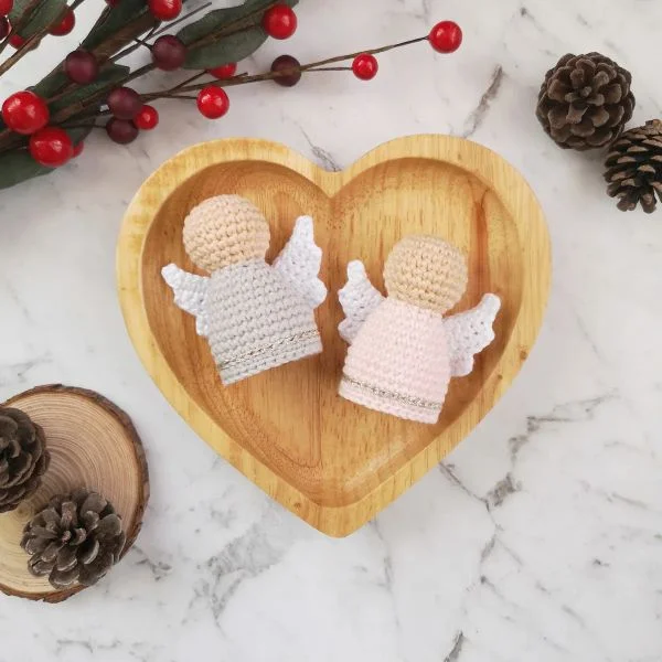 Two crochet angels in a wooden heart shaped bowl.