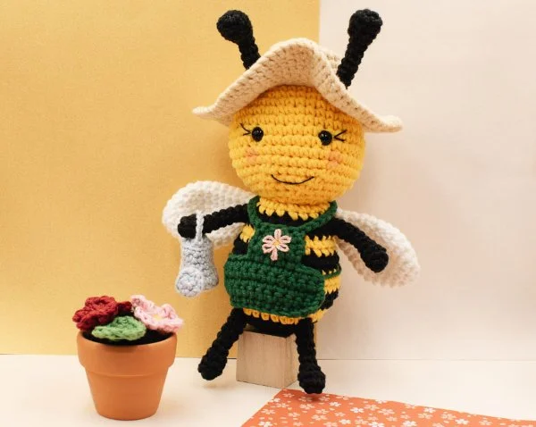 Amigurumi Bee wearing a gardening apron and hat.