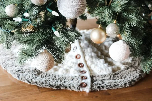 Christmas tree with baubles on a crocheted tree skirt with buttons.