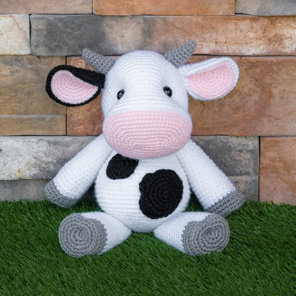 Crochet cow softie with balck spots.