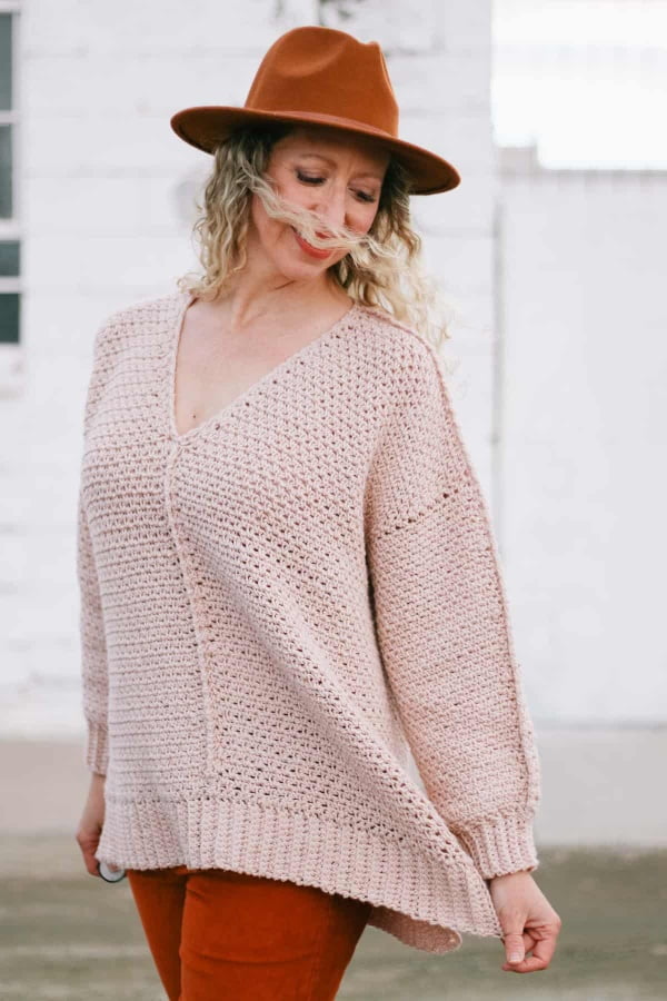 Pink v-neck crochet sweater with high-low hem.
