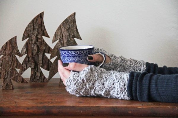 Person holding a cup of tea while wearing lacy crochet fingerless gloves