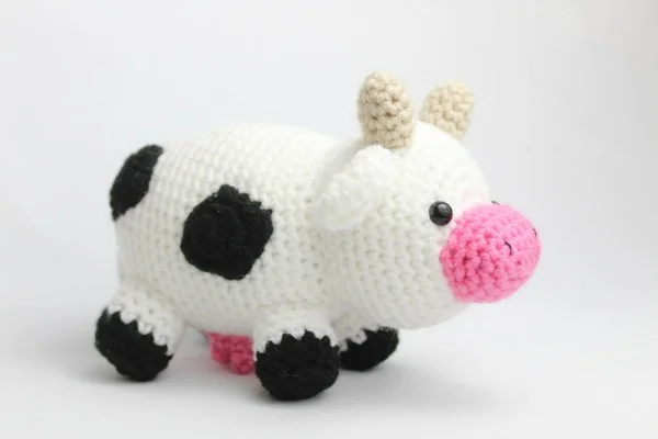 Standing cow amigurumi with horns and udder.