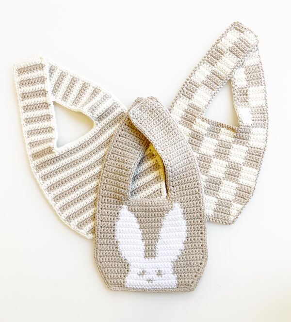 Three crocheted baby bibs in neutral colors.