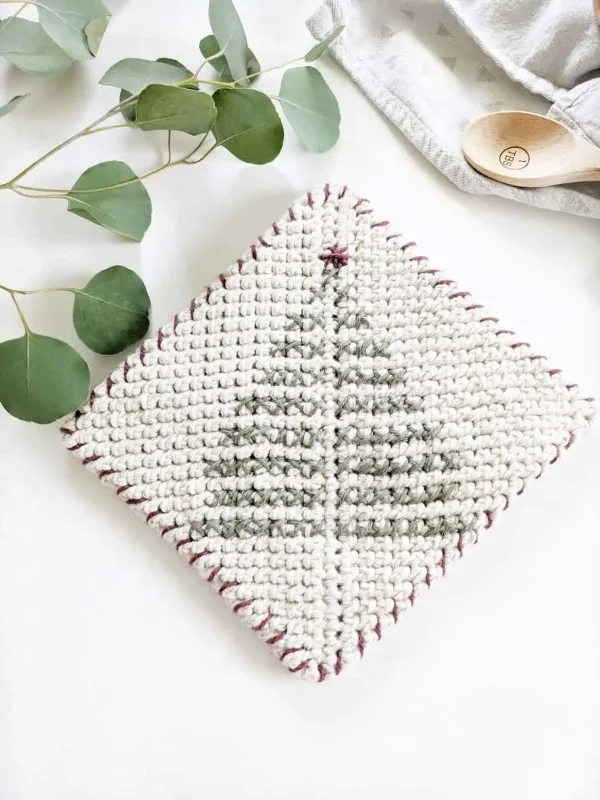 Crochet potholder with Christmas tree embroidery.