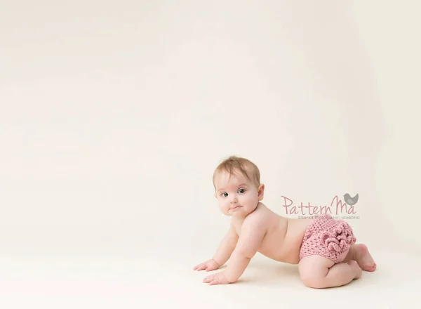 Baby girl wearing a frilly pink crochet diaper cover.