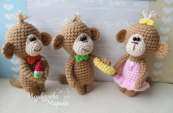 Three crochet monkeys; one wearing a scarf, one wearing a bow tie, and one wearing a pink dress.