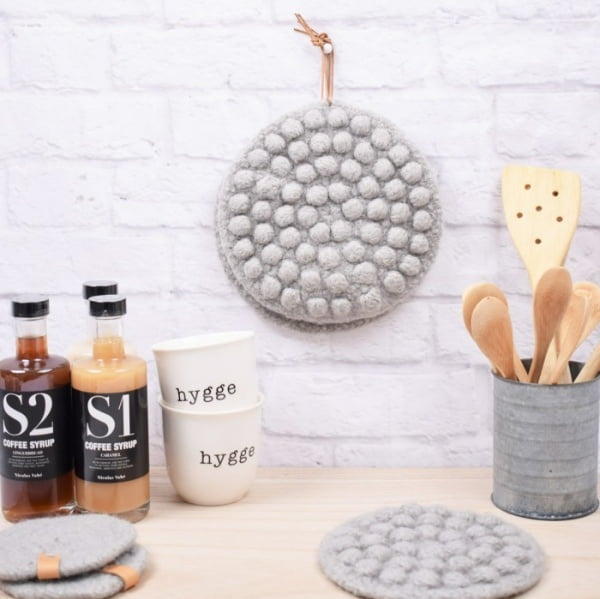 Felted crochet potholders hanging in a kitchen.