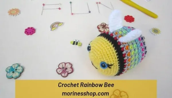 Crochet bee amigurumi with rainbow body and blue eyes.