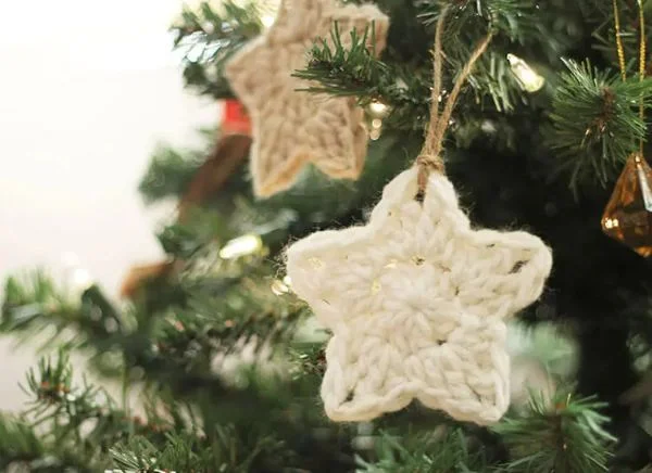 Crochet star ornaments hanging on a Christmas tree.