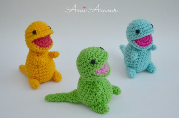 Three little crocheted dinosaurs with open mouths.