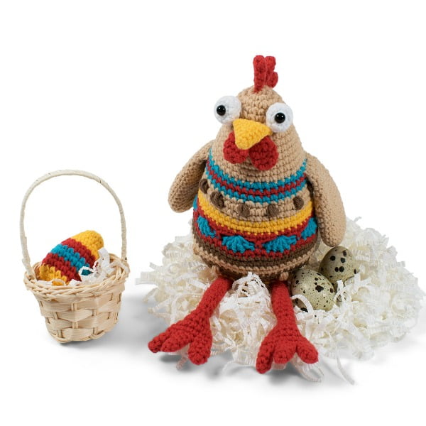 Crochet chicken sitting on eggs in a nest.