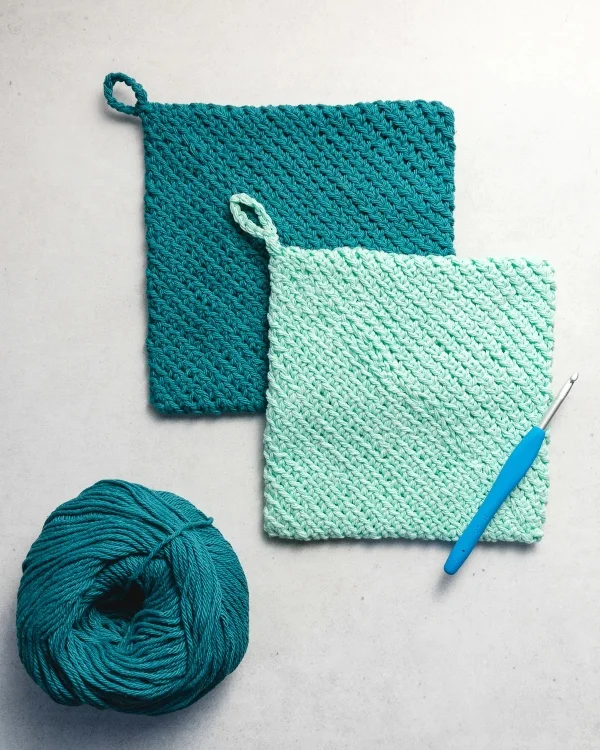 Two crochet potholders, yarn, and a crochet hook.