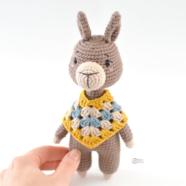 Crochet amigurumi llama wearing a poncho.