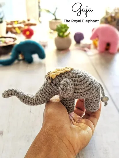 Gray crochet elephant with a long trunk and Indian headdress.