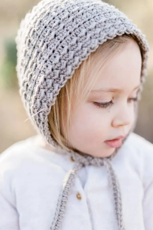Little girl wearing a crocheted bonnet.