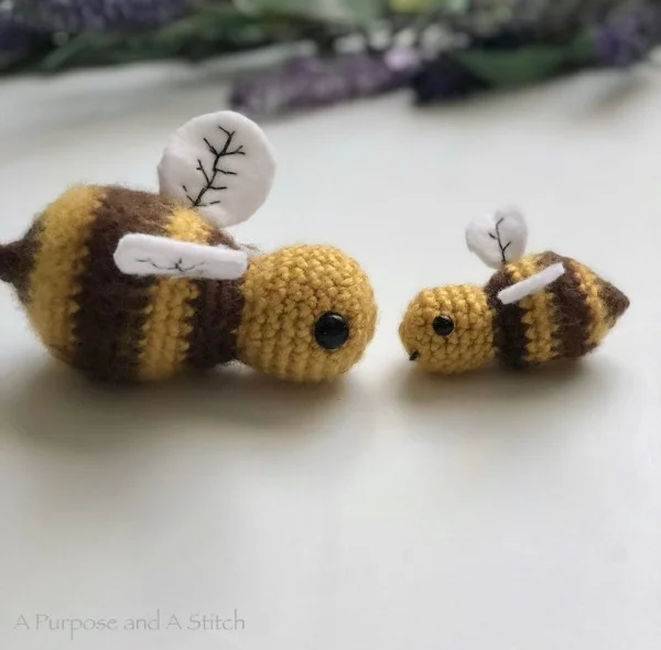 A mother bee and a baby bee amigurumi with embroidered detail on wings.