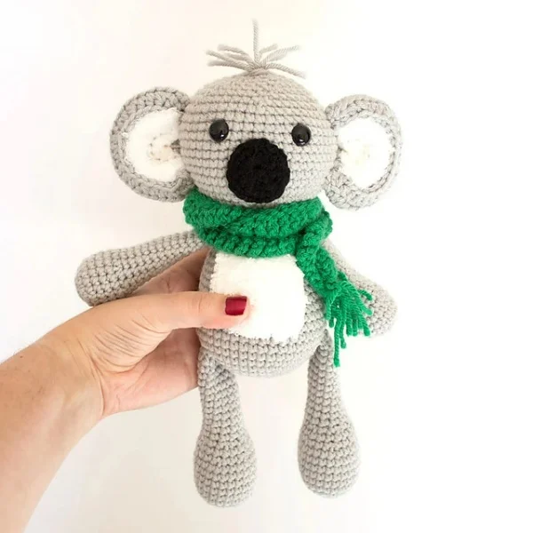 Amigurumi crochet koala wearing a green scarf.