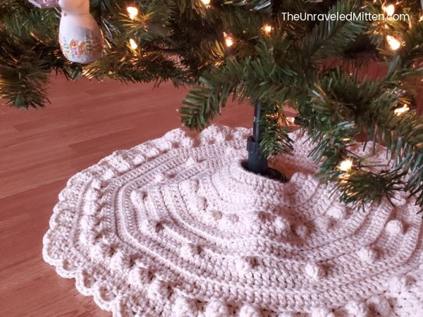 Crocheted white Christmas tree skirt with bobble stitch and scalloped edging.