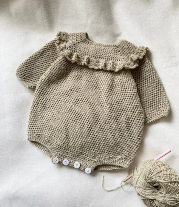 Long-sleeved crochet baby romper with ruffle bodice.