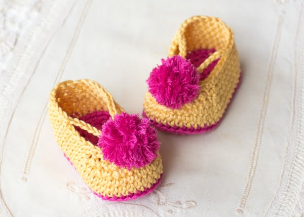 Crochet baby booties with pom-pom.