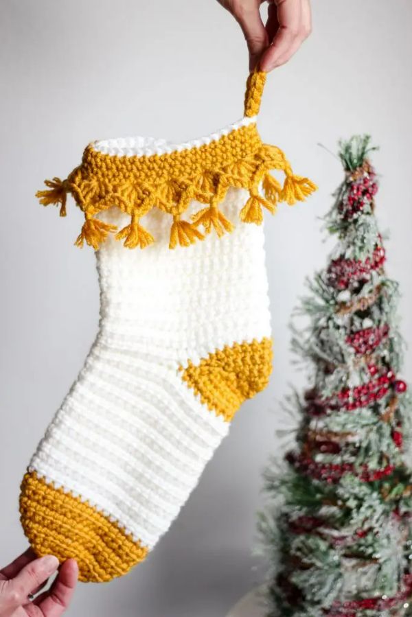 Yellow and white crochet Christmas stocking with tassels.