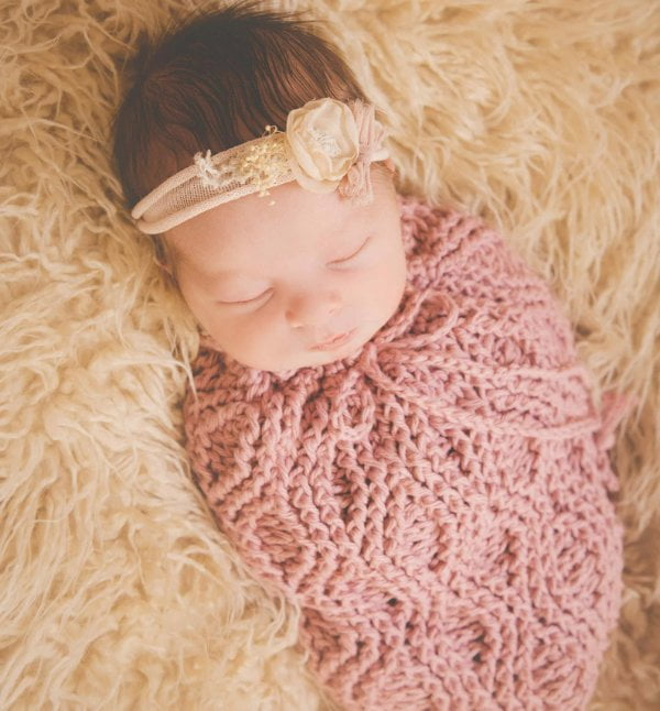 Newborn baby in pink crochet baby cocoon.