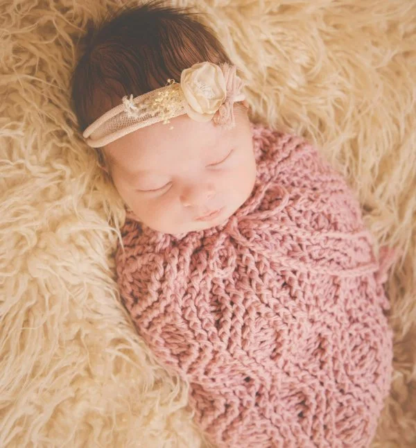 Newborn baby in pink crochet baby cocoon.