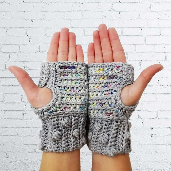 Hands wearing fingerless gloves iwth braided crochet design.