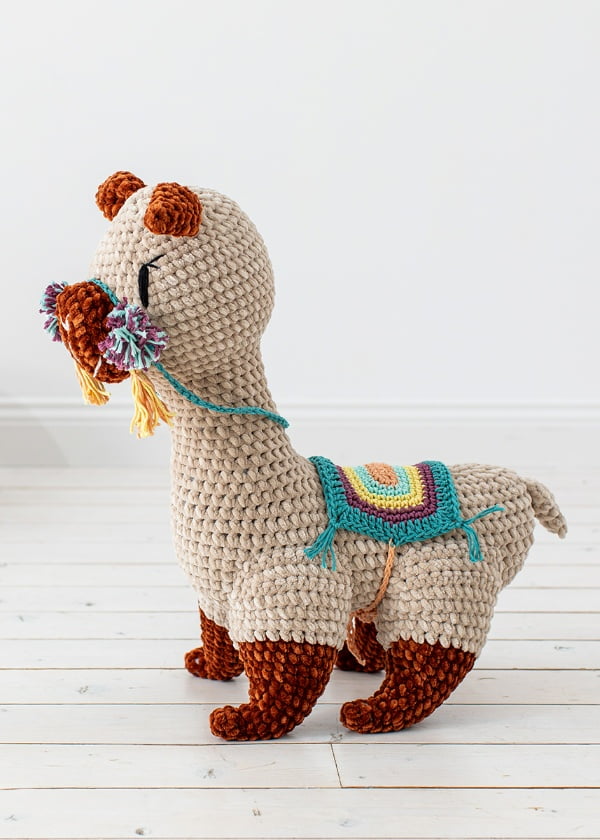 Crochet alpaca with colorful saddle blanket and reins.