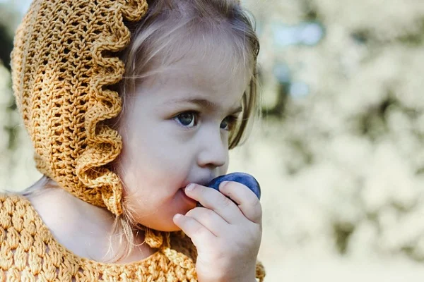 Little girl in golden yellow bonnet with frilled edge.