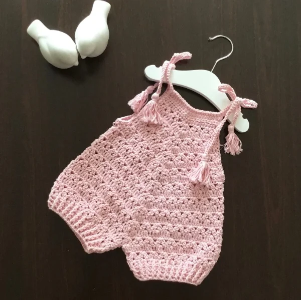 Pink crochet baby romper with tie straps.