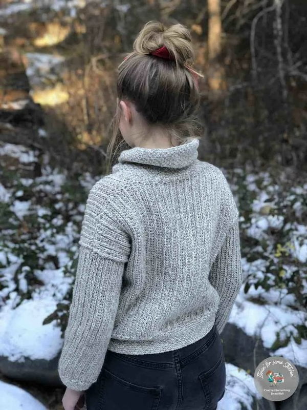 Woman wearing crochet cowl neck sweater outside.