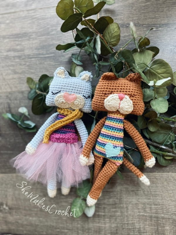 Two colorfully dressed crochet cats with long arms and legs.