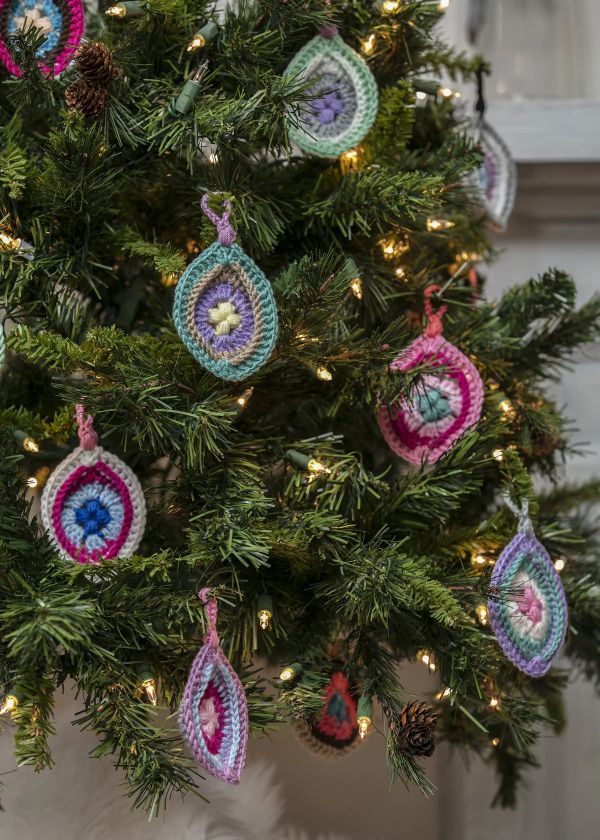 Crochet for design of fir tree. Pink and purple yarn for crocheting  christmas decoration on fir tree. Crochet homemade decor for xmas tree. How  to make crochet toys at home. Photos
