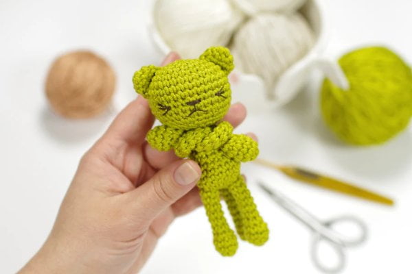 Green crochet cat with long legs and arms.
