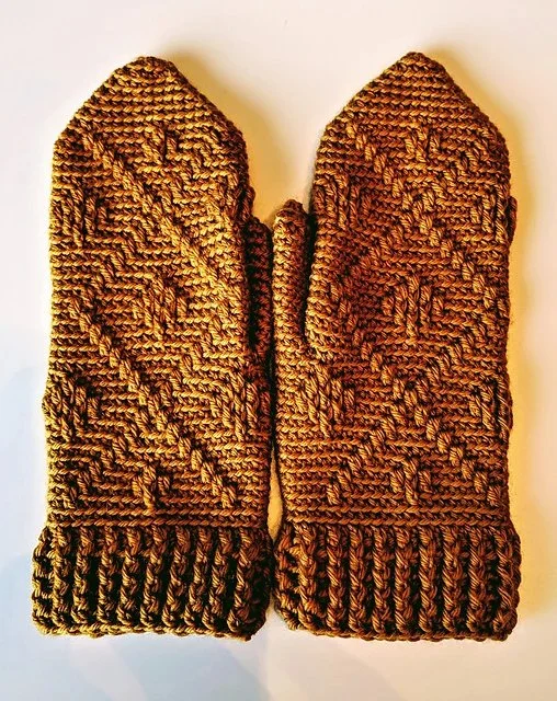 A pair of crochet mittens with a geometric design.