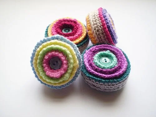 Four colorful round crochet pincushions.