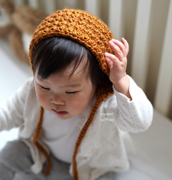 Baby wearing an autumn colored crochet baby bonnet.