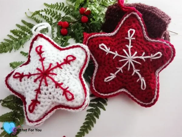 Red and white crochet stars Christmas ornaments with embroidery embellishments.