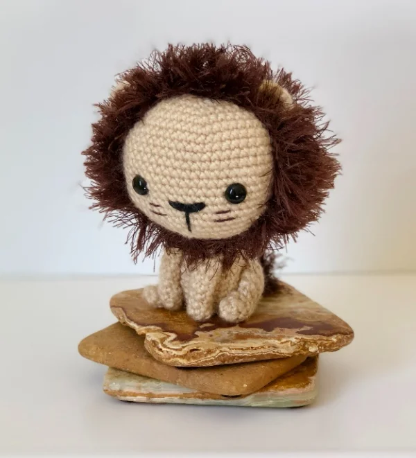 Little crochet lion sitting on a stack of rocks