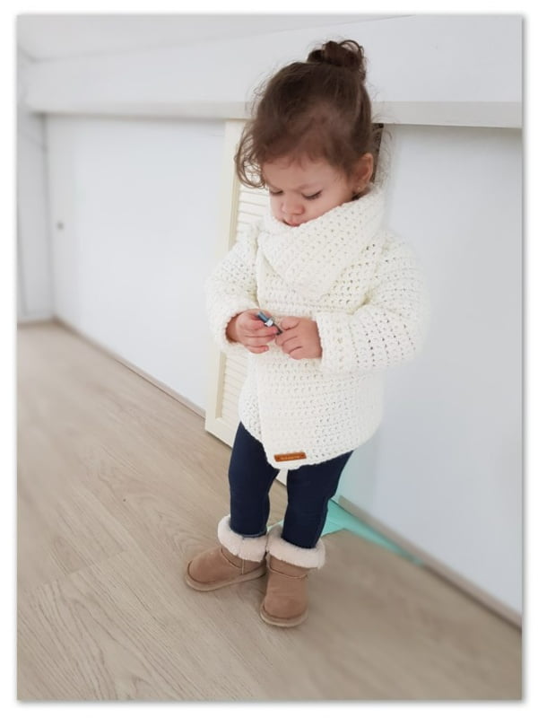 Little girl wearing oversized crochet jacket with collar.