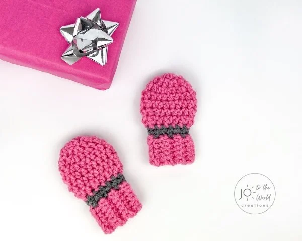 Bright pink crochet baby mittens.