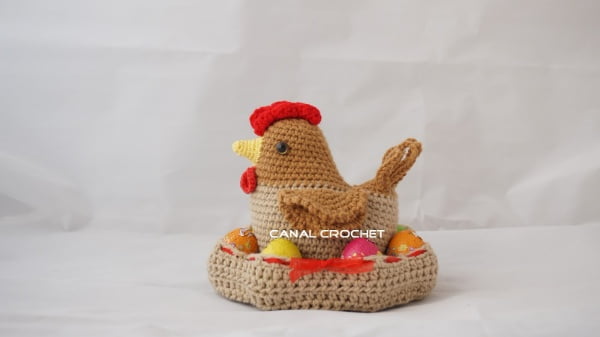 Crochet hen sitting on a nest of easter eggs.
