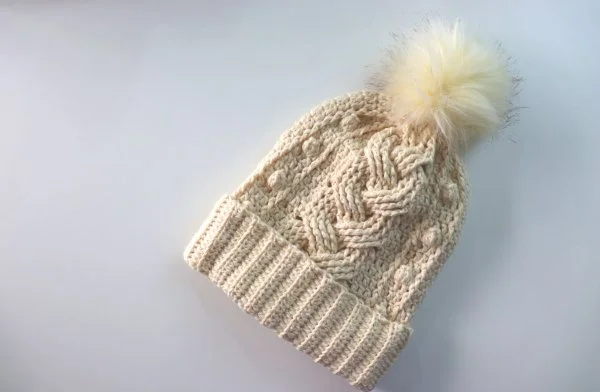 A crocheted cable beanie with popcorn stitch detail.